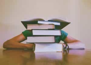 man-sitting-behind-pile-of-books